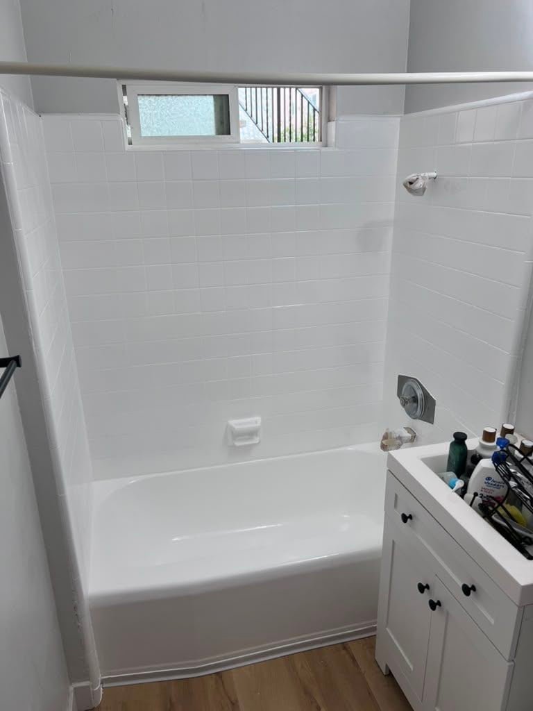 Refinished white bathtub with new tiles and fixtures in La Jolla bathroom.